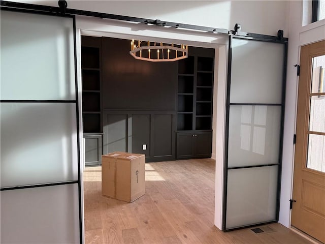 kitchen featuring freestanding refrigerator, visible vents, light wood-style flooring, and a barn door