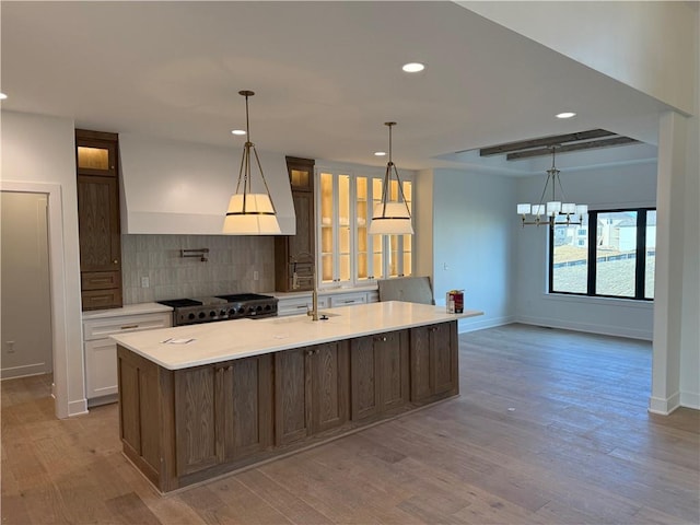 kitchen featuring tasteful backsplash, range, a large island, light countertops, and light wood-style floors