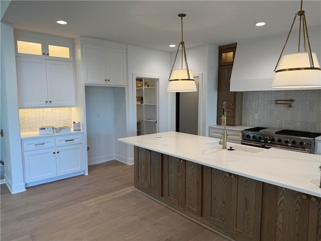 kitchen with range with two ovens, white cabinetry, light wood-style floors, and glass insert cabinets