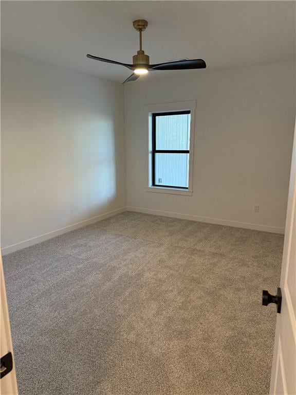 carpeted empty room featuring ceiling fan and baseboards