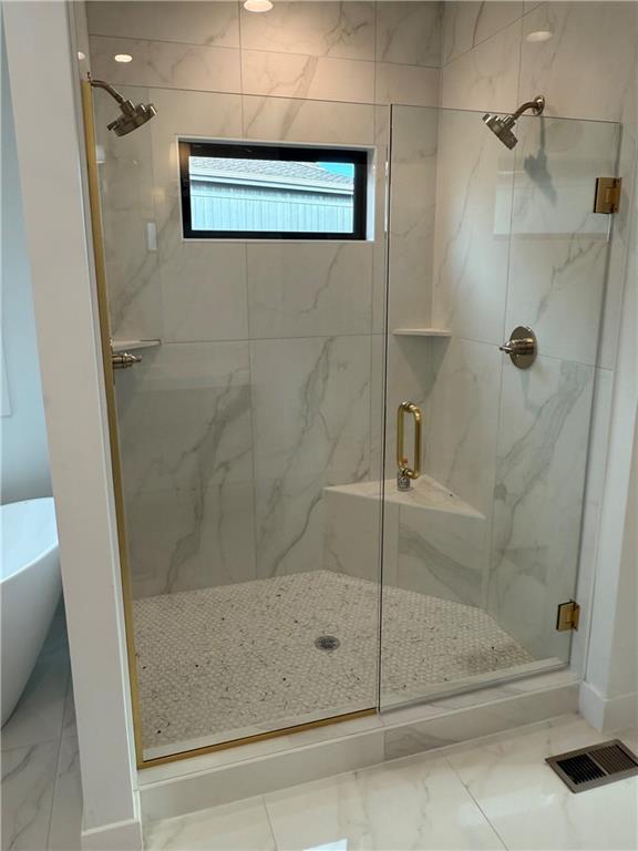 bathroom featuring a freestanding bath, marble finish floor, a marble finish shower, and visible vents