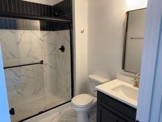 bathroom with toilet, a marble finish shower, and vanity