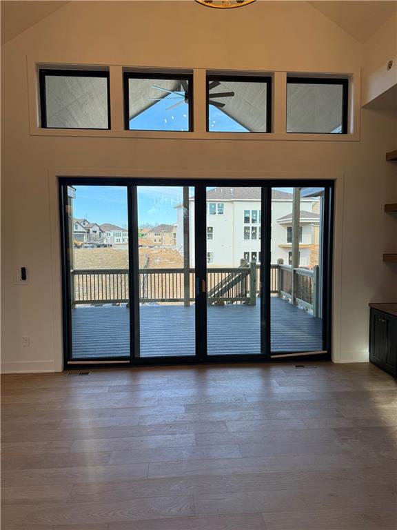 doorway with high vaulted ceiling and wood finished floors