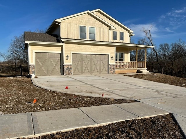 craftsman-style house featuring stone siding, a porch, board and batten siding, and concrete driveway