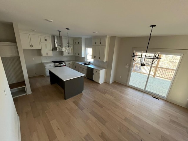 kitchen with light wood finished floors, tasteful backsplash, appliances with stainless steel finishes, wall chimney range hood, and a sink