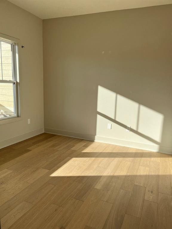 spare room featuring baseboards and wood finished floors