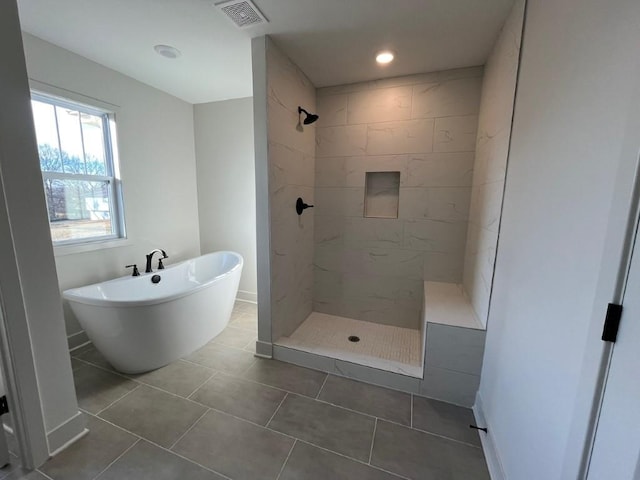 bathroom featuring a freestanding tub, visible vents, tiled shower, and tile patterned floors