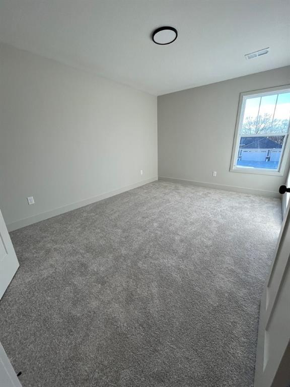 empty room with baseboards, visible vents, and carpet flooring