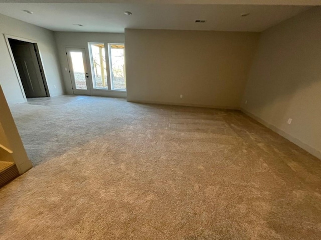 spare room featuring light carpet, visible vents, and baseboards