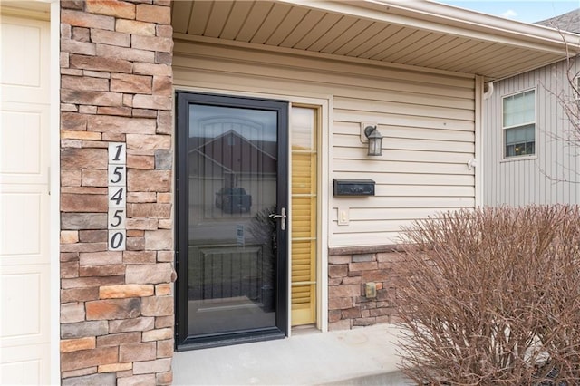 view of exterior entry with a garage and stone siding