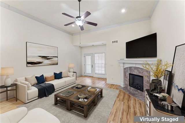 living room with a fireplace, visible vents, wood finished floors, and ornamental molding