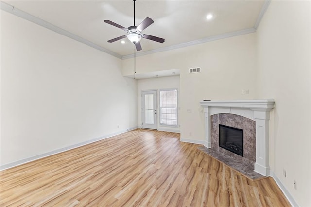 unfurnished living room with visible vents, ornamental molding, wood finished floors, a tile fireplace, and baseboards