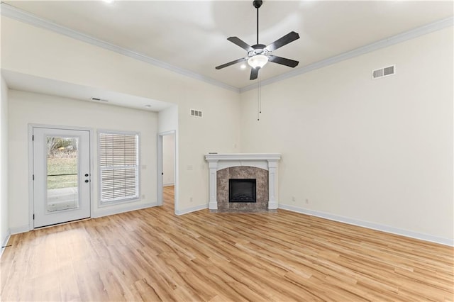 unfurnished living room featuring a tile fireplace, visible vents, crown molding, and light wood-style flooring