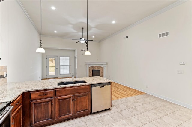 kitchen with stainless steel appliances, a sink, visible vents, a tiled fireplace, and crown molding