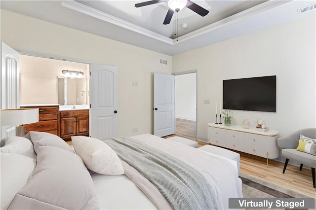 bedroom featuring light wood finished floors, visible vents, a tray ceiling, and ornamental molding