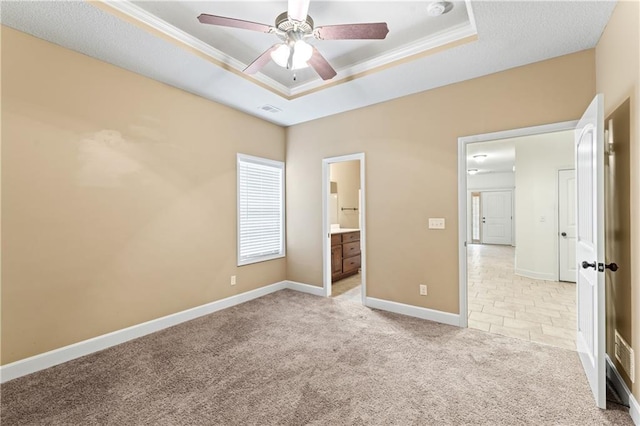 unfurnished bedroom featuring light colored carpet, baseboards, ornamental molding, a raised ceiling, and ensuite bath