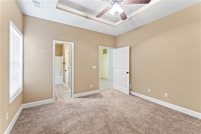 unfurnished bedroom featuring a tray ceiling, carpet flooring, visible vents, and baseboards