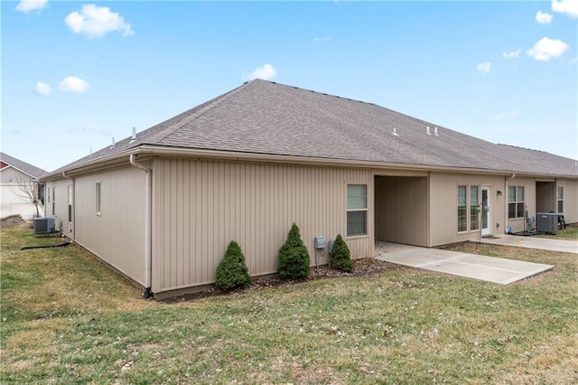 rear view of property featuring a patio, central AC unit, a lawn, and a shingled roof