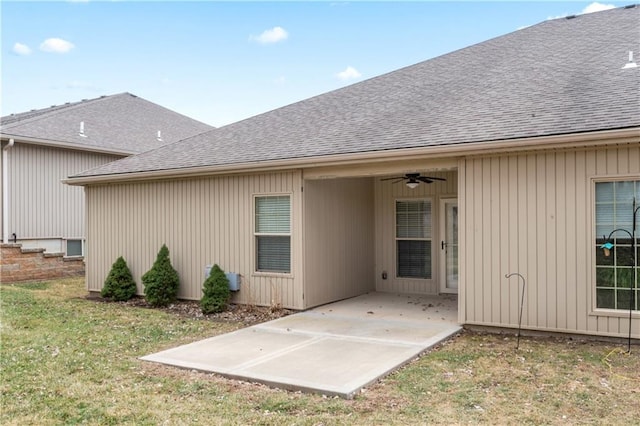 rear view of property featuring a patio area, ceiling fan, a shingled roof, and a yard