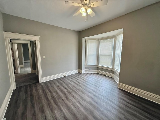 empty room with dark wood finished floors, baseboards, and ceiling fan