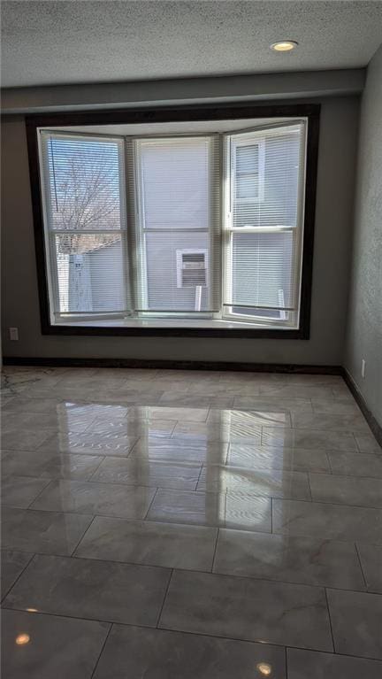 empty room with a textured ceiling and baseboards