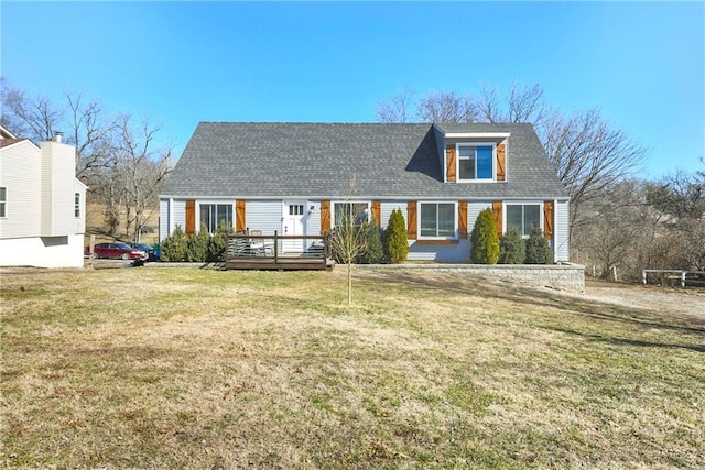 view of front of property featuring a shingled roof, a front yard, and a wooden deck