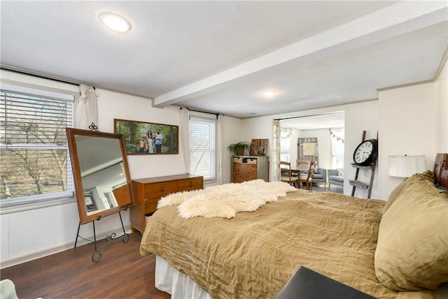 bedroom featuring baseboards, dark wood finished floors, and beamed ceiling