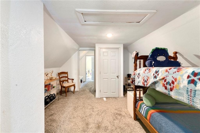 bedroom with attic access, lofted ceiling, and carpet flooring