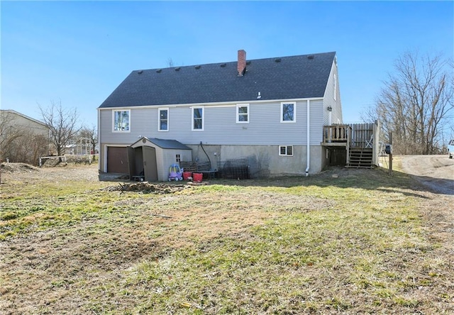 rear view of property featuring an attached garage, a yard, stairway, a wooden deck, and a chimney