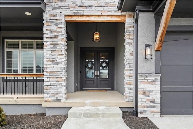 entrance to property featuring a porch, a garage, brick siding, stone siding, and french doors