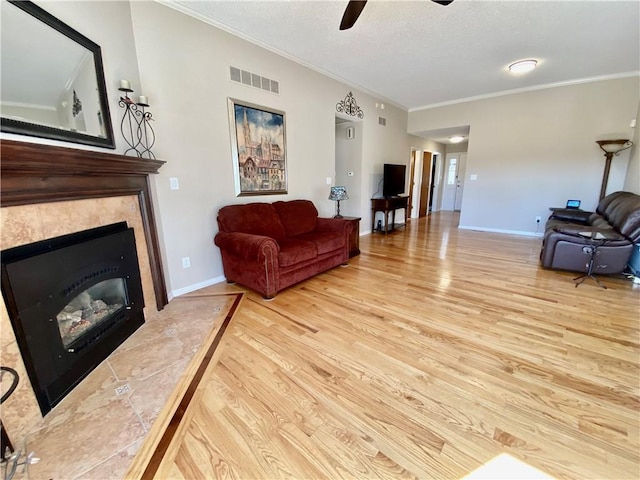 living room featuring visible vents, crown molding, baseboards, wood finished floors, and a textured ceiling