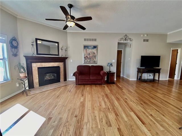 living area with a premium fireplace, light wood-style flooring, visible vents, and a textured ceiling