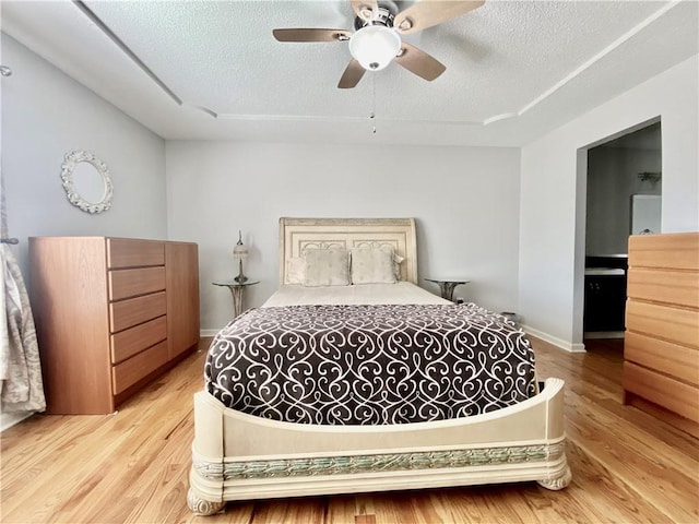 bedroom with ceiling fan, light wood-style flooring, baseboards, and a textured ceiling