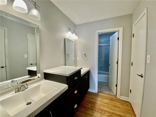 full bath featuring bathtub / shower combination, vanity, wood finished floors, and a textured ceiling