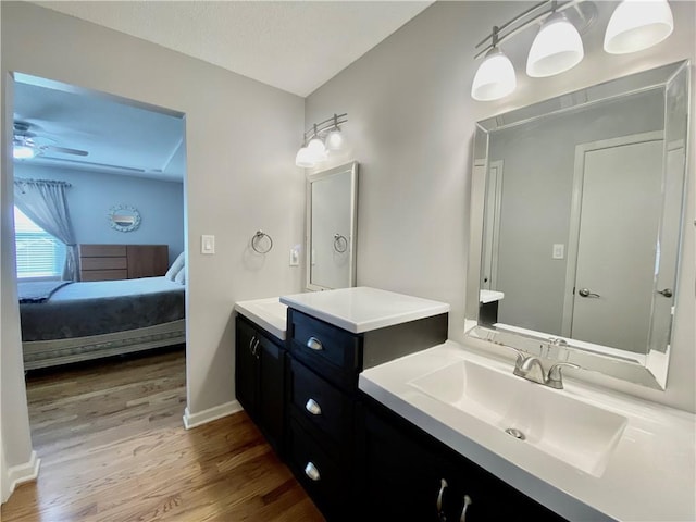 ensuite bathroom featuring wood finished floors, ensuite bath, baseboards, ceiling fan, and vanity