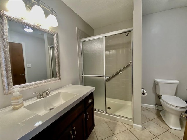 full bath with vanity, baseboards, tile patterned flooring, a shower stall, and toilet