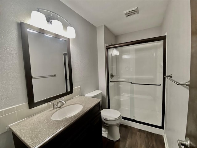 full bath with visible vents, a shower stall, toilet, wood finished floors, and vanity