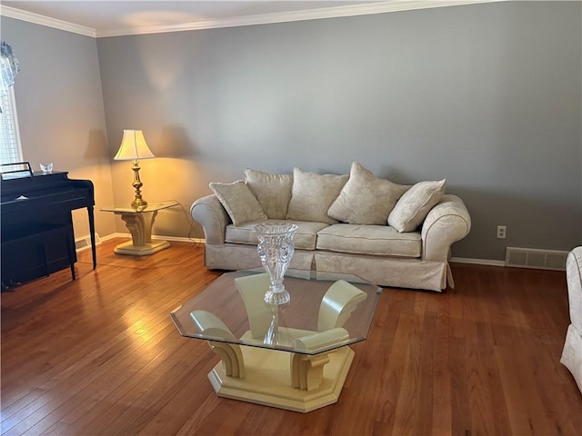 living room with hardwood / wood-style floors, baseboards, visible vents, and crown molding