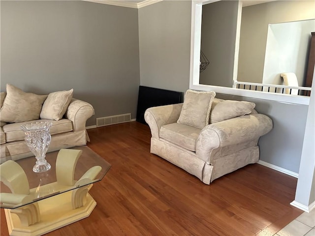 living room featuring ornamental molding, wood finished floors, visible vents, and baseboards