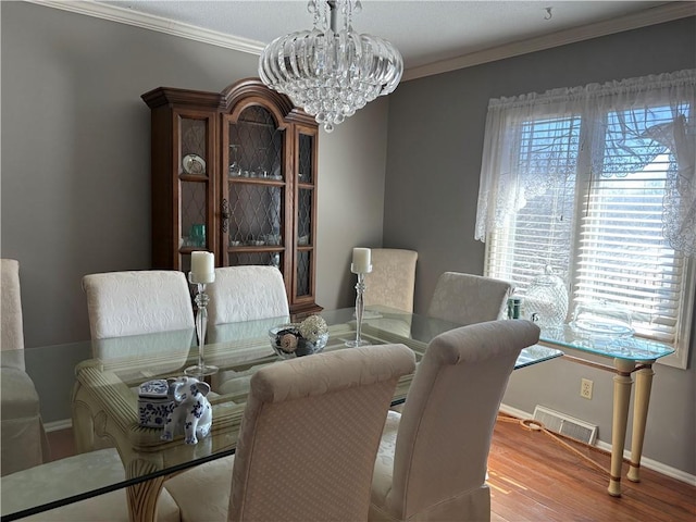 dining area with baseboards, visible vents, wood finished floors, crown molding, and a chandelier