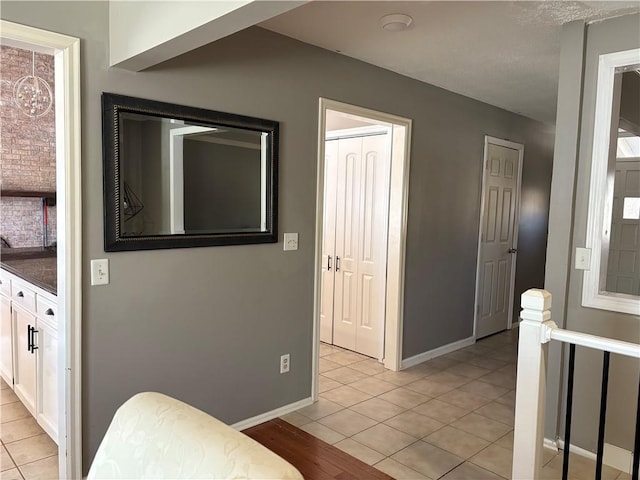 interior space featuring dark countertops, light tile patterned floors, baseboards, and white cabinetry