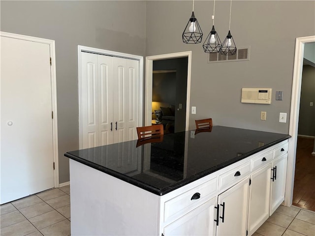 kitchen featuring light tile patterned floors, a peninsula, visible vents, white cabinets, and hanging light fixtures