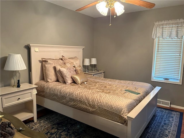 bedroom featuring a ceiling fan, dark wood-style flooring, visible vents, and baseboards