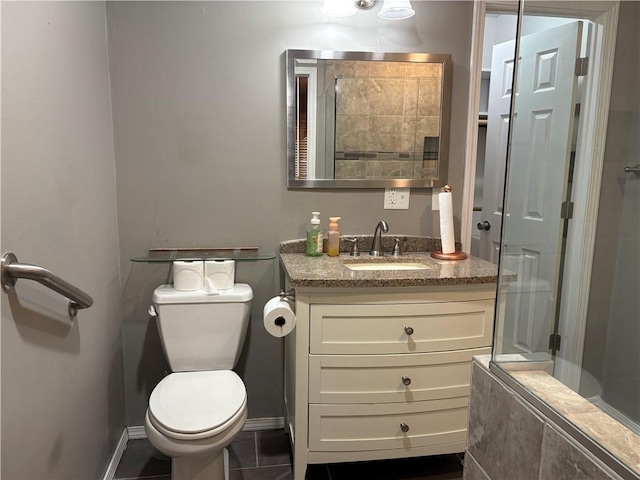 bathroom featuring baseboards, a shower with shower door, vanity, and toilet