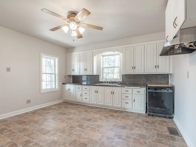 kitchen with visible vents, baseboards, dark countertops, a sink, and backsplash