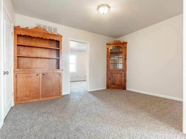 spare room featuring carpet flooring, visible vents, and baseboards