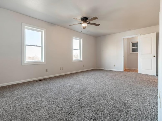 carpeted spare room with ceiling fan, visible vents, and baseboards