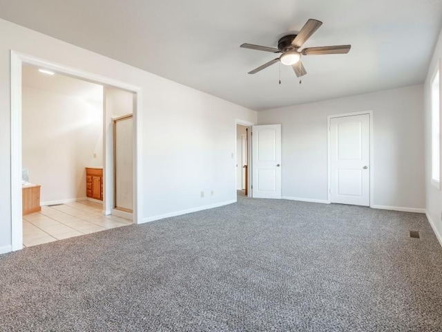 unfurnished bedroom with visible vents, carpet flooring, ensuite bath, baseboards, and tile patterned floors