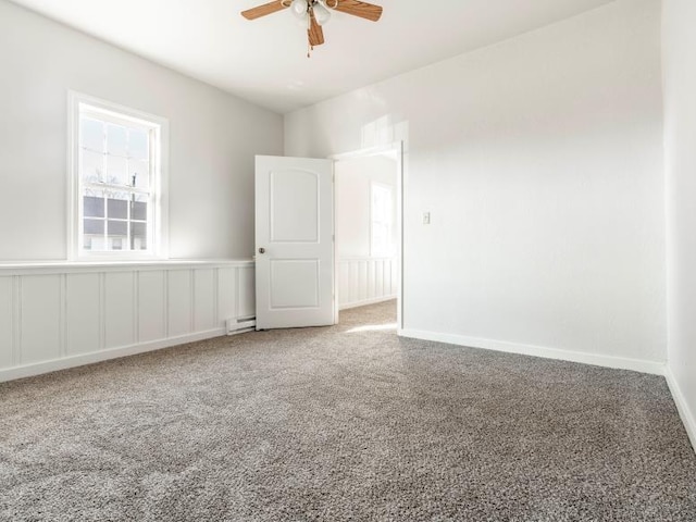 spare room featuring carpet, ceiling fan, baseboards, and a baseboard radiator