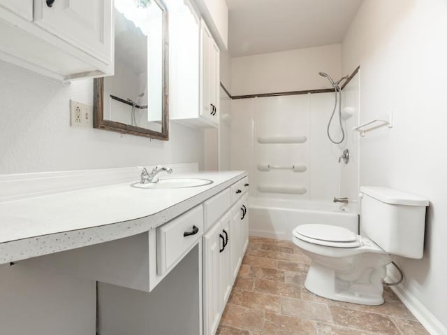 full bath with toilet, stone finish floor, vanity,  shower combination, and baseboards